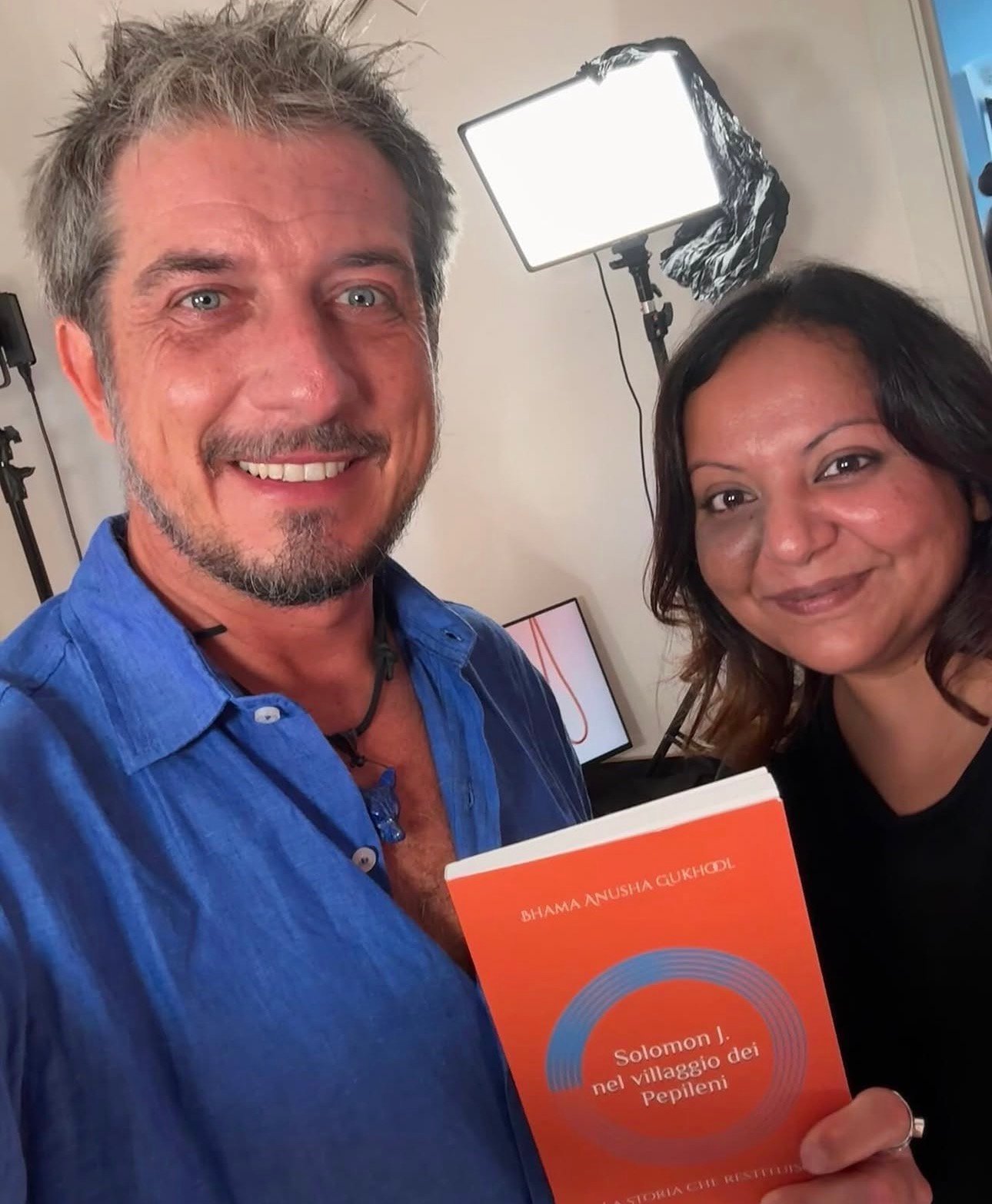 Anusha Bhama Gukhool con Paolo Ruffini sul set del programma Mamme, con in mano il libro Solomon J. nel villaggio dei Pepileni